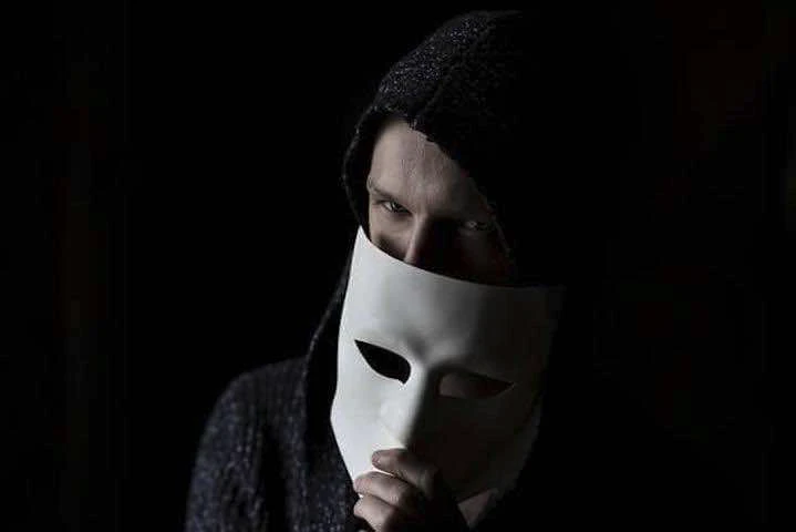 Un homme a capuche noire et masque blanc.